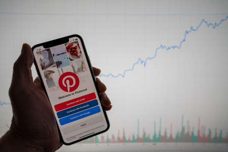 Pinterest app on phone with white financial stock chart with price rising upward positive in backgroundのeditorial素材