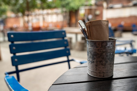 Steel bucket containing napkins and utensils in restaurant on table