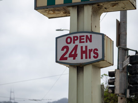 Open 24 hours sign hanging on store billboard sign outside a shopping center