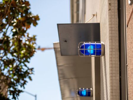 Blue caution safety lights affixed to a building outside and positioned highの写真素材