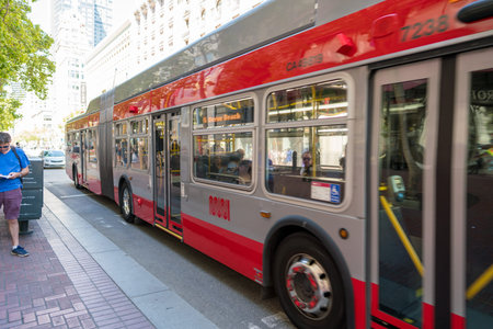Muni bus Fulton line 5 on moving past person at bus stop