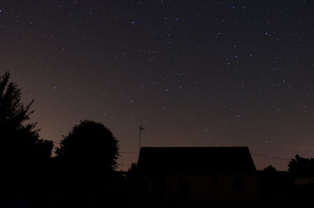 A night sky full of stars with house and trees silhouettesの写真素材