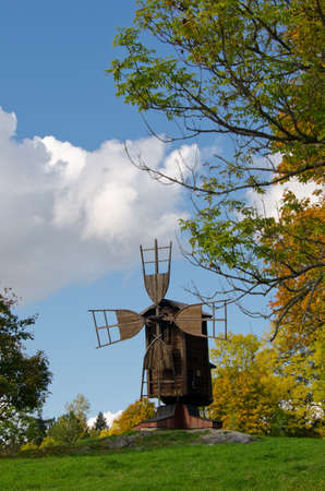 A wooden windmill surrounded by trees with their autumn coloursの写真素材