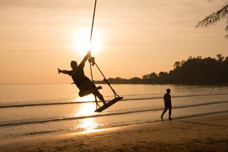 Happy Man on a swing at sunsetの写真素材