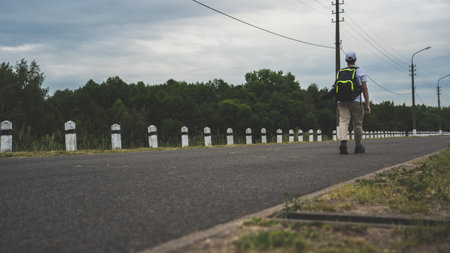 A man walking along a road with concrete pillars along itの写真素材
