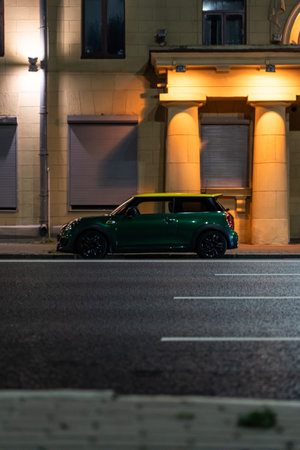 Small car is parked on the side of the road, at night in the cityの写真素材
