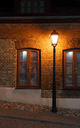 The house is tilted. A street lamp illuminates the windows of the house at nightの写真素材