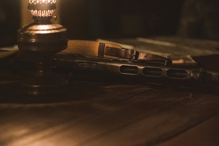 An old rifle lies on a table next to a kerosene lamp in the semi-darknessの写真素材