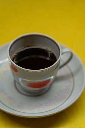 Instant coffee in a mug. A mug in a saucer on a yellow background. Top-down view