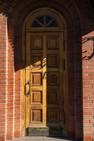 A tall, narrow, old, wooden door. Entrance to the brick buildingの写真素材