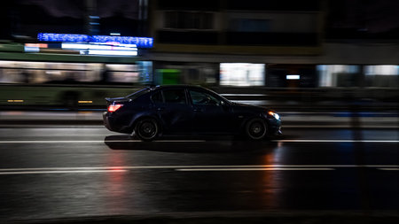 The car drives through the city at night, side view. Motion blur
