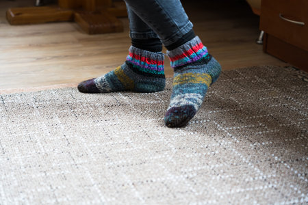 The feet of a girl in wool socks and jeans are standing on the carpet. High quality photoの写真素材