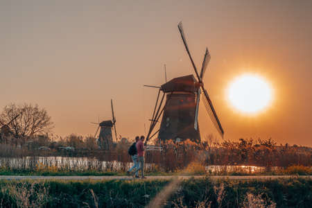 Tourists passing by wind mill in Kinderdijk during sunset near Rotterdamの写真素材