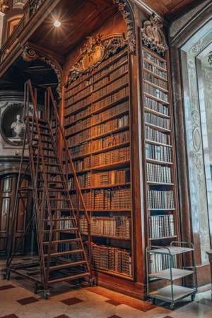 Vienna, Austria - April 28, 2019: Ladders besides antique bookshelf filled with old books inside imperial libraryのeditorial素材