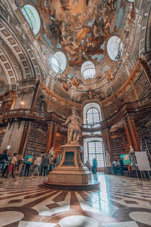 Vienna, Austria - April 28, 2019: Tourists admire the bookshelf and statue Charles VI inside imperial libraryのeditorial素材