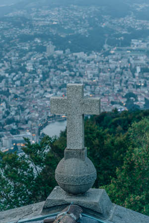 Stone cross of Chapel on top of Monte Salvatore, with city lugano in backgroundの写真素材