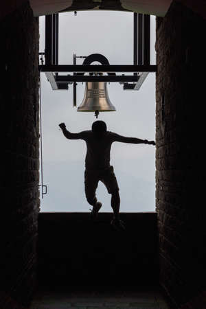 Man jumping off bell in Chapel Santa Maria degli Angeli on top of Monte Tamaroの写真素材