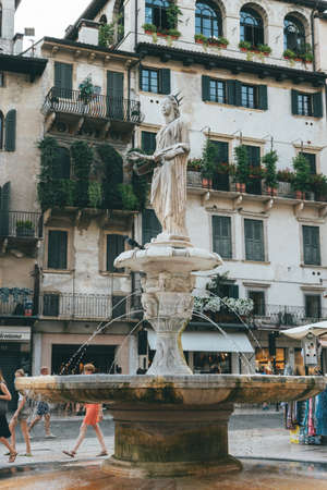 Verona, Italy - August 6, 2019: People walk by an old medieval Fontana Madonna Verona on the streetのeditorial素材