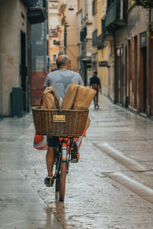 Verona, Italy - August 7, 2019: Italian man ride bicycle on the street with bread in the back, in the early morningのeditorial素材