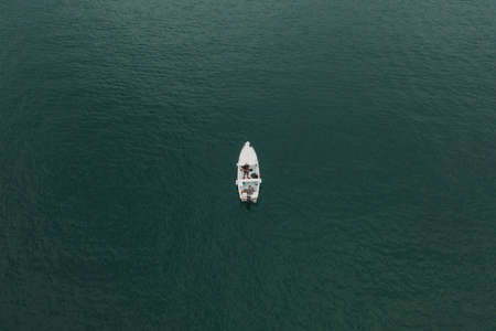 Malcesine, Italy - August 7, 2019: Aerial drone shot view of two men in a white boat in lake gardaのeditorial素材