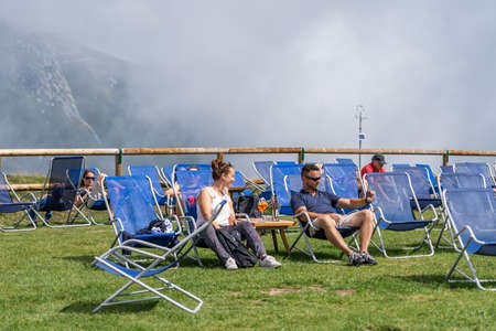 Monte Baldo, Italy - August 8, 2019: Tourists hiker rest in deck chair in the morning sun on monte baldo by lake gardaのeditorial素材