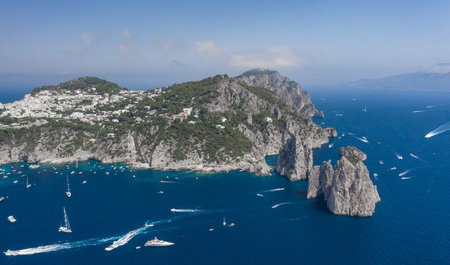 Aerial drone shot view of southern coastline of Capri Islan in Tyrrhenian sea with yachts