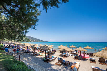 Zakynthos, Greece - August 19, 2019: Tourists enjoy summer at each resort with umbrella and bed in Porto Azzuro beach barのeditorial素材