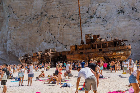 Zakynthos, Greece - August 20, 2019: Tourists enjoy summer noon in front of rusty abandoned ship in Shipwreck bay navagio beachのeditorial素材