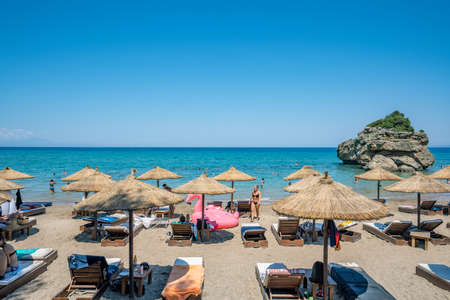 Zakynthos, Greece - August 19, 2019: Tourists enjoy summer at each resort with umbrella and bed in Porto Azzuro beach barのeditorial素材