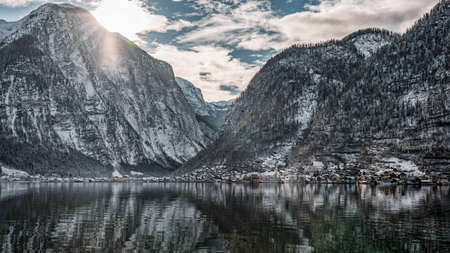 Snowy village Hallstatt at the foot of mountain with sunny sky in winter in Austriaの写真素材