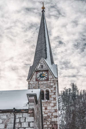 Snowy Evangelical church clock tower in Hallstatt, Austria in winterの写真素材