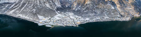 Aerial panoramic drone shot of snowy Lahn and Hallstatt village by lake in Austria during winterの写真素材