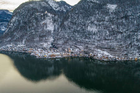 Aerial drone shot of Hallstatt village at foot of snow mountain after sunet in Austria in winterの写真素材
