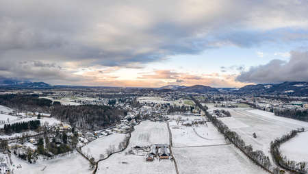Aerial view of Salzburg outskirts snowy villages during sunset hour with clouds after snow storm in winter timeの写真素材