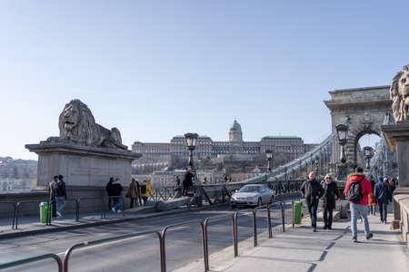 Tourists on Szechenyi chain bridge with view of Buda Castle in far endのeditorial素材