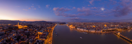 Panoramic aerial drone shot of Danube river with lighted quai with purple sky during Budapest sunset. High quality photoの写真素材