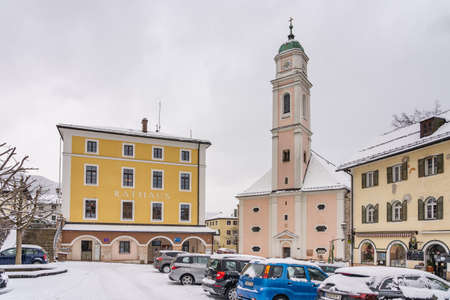 Snow covered church Kath. Kirche St. Andreas with town hall parkingのeditorial素材