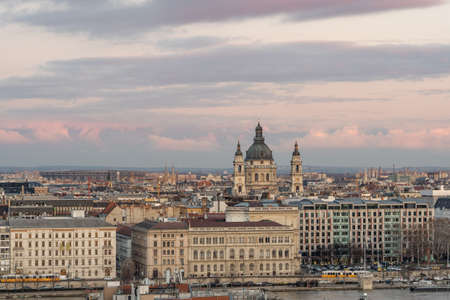 Danube river side view of St. Stephen's Basilica at dusk with yellow tram carriage in winterの写真素材