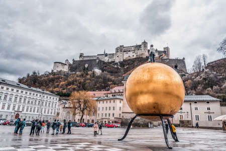 Tourists take photo of golden ball in square besides Salzburg Cathedralのeditorial素材
