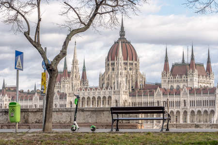 Budapest, Hungary - Feb 10, 2020: Bench and scooter facing Hungarian Parliament by Danube. High quality photoのeditorial素材
