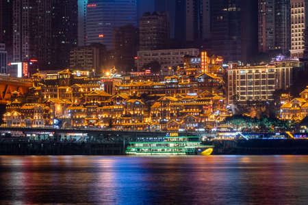 Chongqing, China - Dec 22, 2019: Night neon light view of cruise ship near historic architecture in Hongya caveのeditorial素材