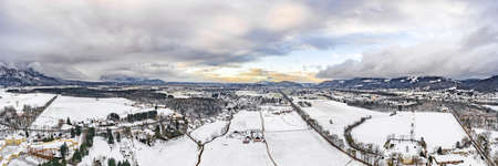 Panoramic aerial view of Salzburg outskirts snowy villages during sunset hour with clouds after snow storm in winterの写真素材