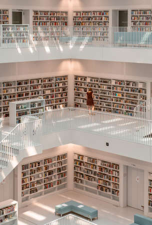 Stuttgart, Germany - Aug 1, 2020 - Woman with mask reads books at Stadtbibliothek library with sun light in the morningのeditorial素材