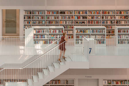 Stuttgart, Germany - Aug 1, 2020 -Librarian with mask walk on stairs in Stadtbibliothek library in the morningのeditorial素材