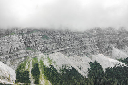 Aerial drone shot of rock cliff of Zugspitze covered with heavy fog in Germanyの写真素材