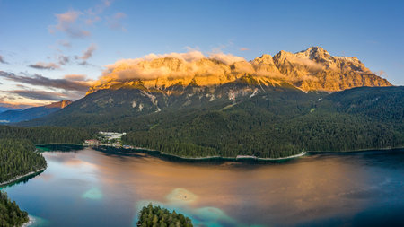 Aerial drone shot of Alpenglow with fog on Zugspitze by Eibsee lake in Germanyの写真素材