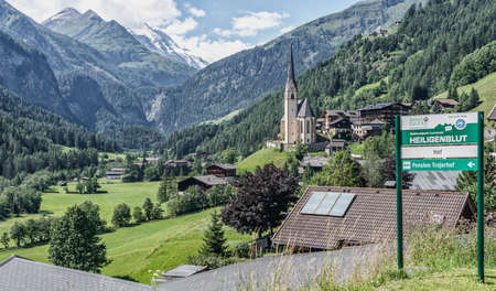 Heiligenblut, Austria - Aug 8, 2020: Town sign of Heiligentblut with blurred St. Vincent church in backgroundのeditorial素材