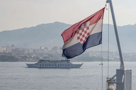 Split, Croatia - Aug 15, 2020: Ferry in Adriatic sea with blurred Croatian flag in the wind in foregroundのeditorial素材