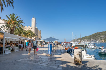 Komiza, Croatia - Aug 16, 2020: Tourists walk on old town port in sunny afternoonのeditorial素材