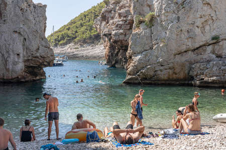 Vis, Croatia - Aug 17, 2020: Tourists sunbathing on sheltered cove Stiniva beach in summerのeditorial素材